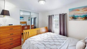 Ein Schlafzimmer mit einem Bett, einem Holzschrank, einem Spiegel und einem Bild an der Wand.