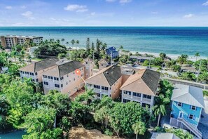 A coastal residential area with multiple two-story houses, a beach, and a clear view of the ocean. - Family-Friendly, Gulf View Condo w/ Pool - Walk to the Beach (Fort Myers Beach)