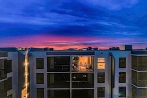 A modern building with multiple floors, large windows, and a view of the sky.