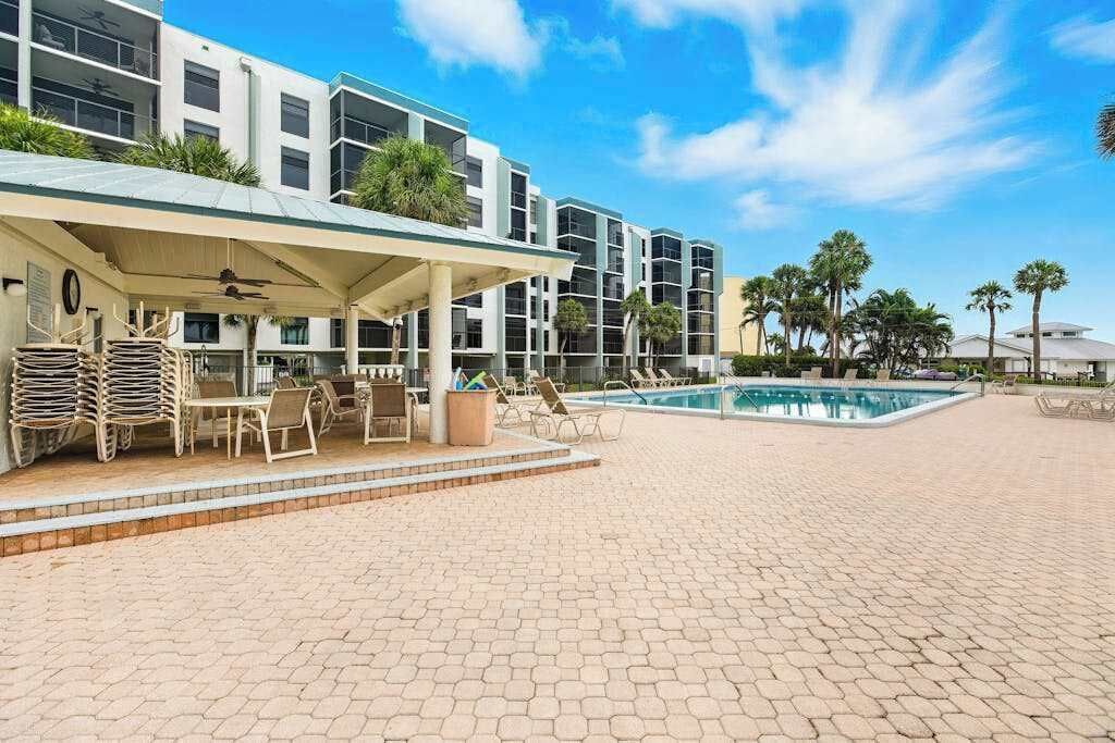 A hotel with a pool, outdoor seating, and a covered area.
