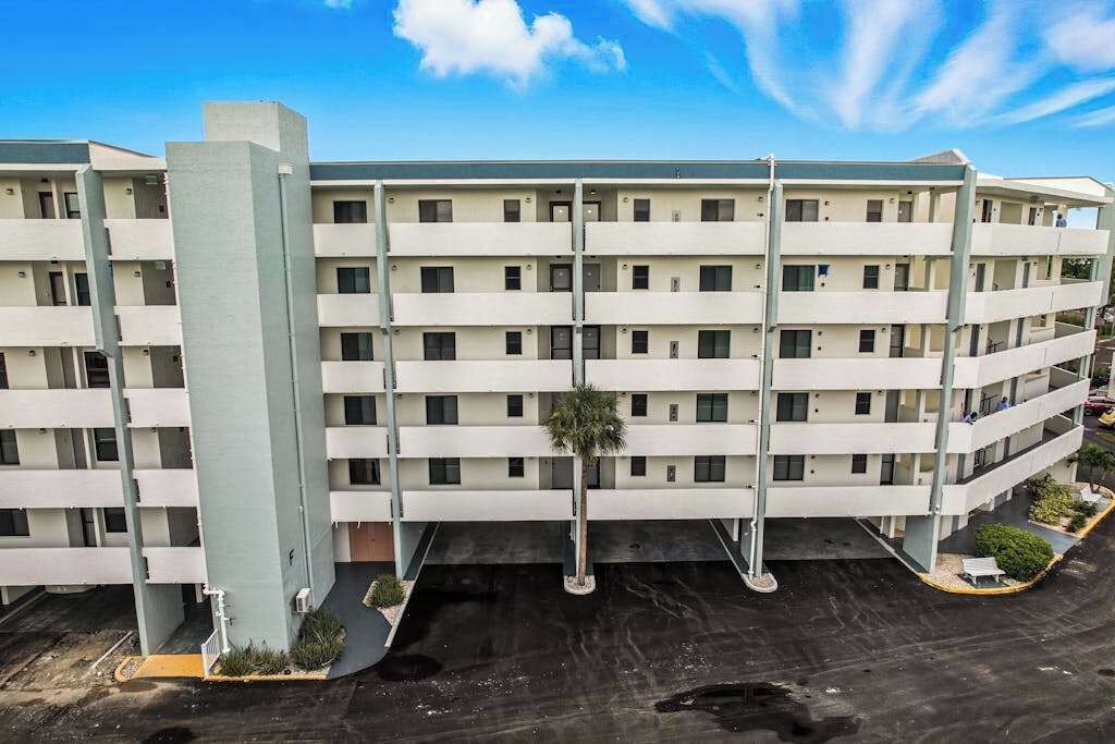 Un hôtel à plusieurs étages doté d’une cour int érieure, de balcons et d’un espace de stationnement.