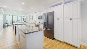 A modern kitchen with white cabinetry, stainless steel appliances, and a large island. - Waterview condo with shared pool, panoramic balcony views, and WIFI (Marco Island)