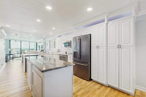 A modern kitchen with white cabinetry, stainless steel appliances, and a large island. - Waterview condo with shared pool, panoramic balcony views, and WIFI (Marco Island)