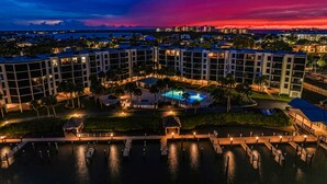 A hotel with multiple buildings, a swimming pool, and a dock area. - Amazing oceanfront condo with pool, hot tub, dock, & views - snowbird-friendly (Marco Island)