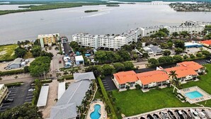 A coastal hotel with multiple buildings, a swimming pool, and a view of the sea. - Amazing oceanfront condo with pool, hot tub, dock, & views - snowbird-friendly (Marco Island)