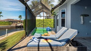 En glasindrammet balkon med pool, liggestole og udsigt over en lysthavn.