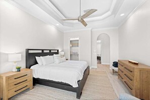 A bedroom with a bed, nightstands, a dresser, a ceiling fan, and a walk-in closet. - Waterfront home with private heated pool, spa, BBQ, views & bikes (Marco Island)