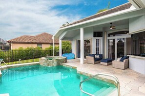A swimming pool with a patio area, outdoor furniture, and a covered section. - Luxurious, waterfront home with private pool/spa (Marco Island)