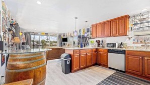 A kitchen with wooden cabinets, a glass-top island, and a view through large windows. - Waterfront home with kayaks, washer/dryer & fast WiFi (Goodland)