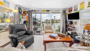 A living room with a black leather sofa, a wooden coffee table, and a TV on a stand. - Waterfront home with kayaks, washer/dryer & fast WiFi (Goodland)