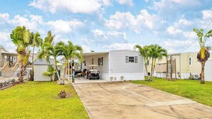 A mobile home with a driveway, palm trees, and a clear sky. - Waterfront home with kayaks, washer/dryer & fast WiFi (Goodland)