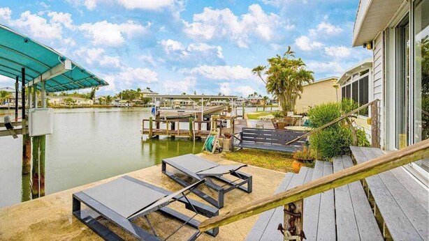 A waterfront patio with lounge chairs, a wooden deck, and a view of the water and dock area. - Waterfront home with kayaks, washer/dryer & fast WiFi (Goodland)