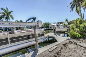 A marina with docked boats, a lift system, and a clear sky. - Canal-front home with private lagoon pool, dock, AC, & W/D - dog-friendly (Marco Island)