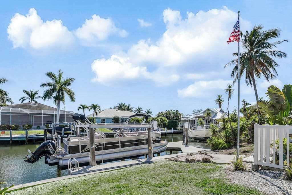 A marina with docked boats, a clear sky, and palm trees.