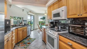 Una cocina con armarios de madera, microondas, estufa y cafetera.