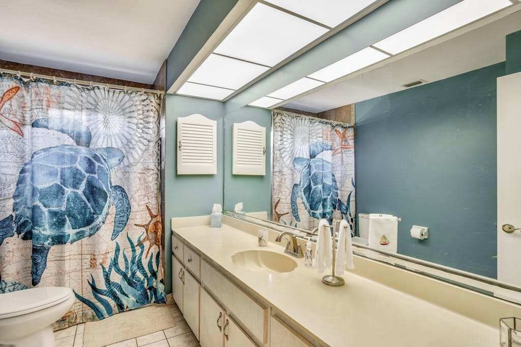 A bathroom with a large mirror, a sink, and a toilet.