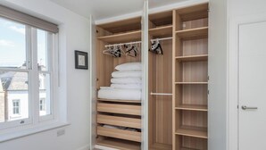 A walk-in closet with wooden shelves, hanging space, and a window. - New 1 Bed Flat Near Central London With Terrace (London)