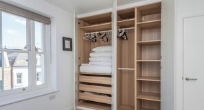 A walk-in closet with wooden shelves, hanging space, and a window. - New 1 Bed Flat Near Central London With Terrace (London)