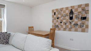 A modern living room with a checkered wall art, a wooden dining table, and a white sofa. - New 1 Bed Flat Near Central London With Terrace (London)