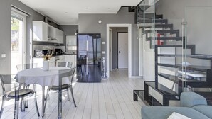 A modern kitchen with a refrigerator, dining table, and chairs. - Open View Apartment by Wonderful Italy (Oliveto Lario)
