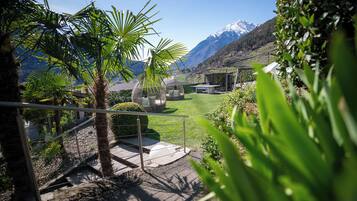 A garden with a seating area, a staircase, and a view of mountains.