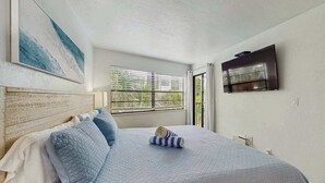 Un dormitorio con una cama, una ventana con persianas, un cuadro y un televisor.