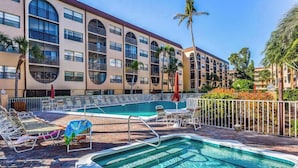 Un hotel con piscina, sillas de sol y palmeras.
