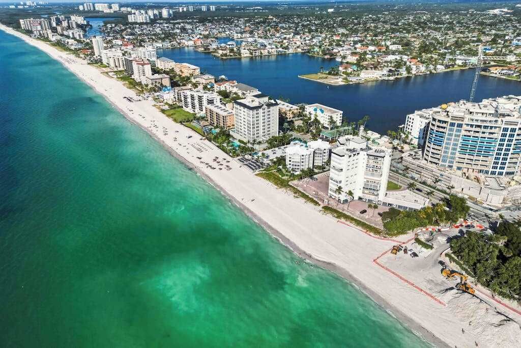 An aerial view of a coastal city with a beach, buildings, and water bodies.