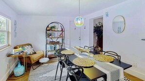 Een eetgedeelte met een tafel voor vier personen, een boekenkast, een bank en een hangende lamp.