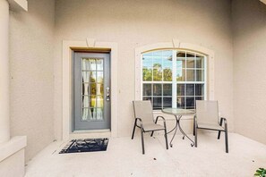 A covered patio with a door, two chairs, and a table. - Relaxing Snowbird-Friendly Retreat Near Golf, Beaches & Outdoor Fun (North Port)