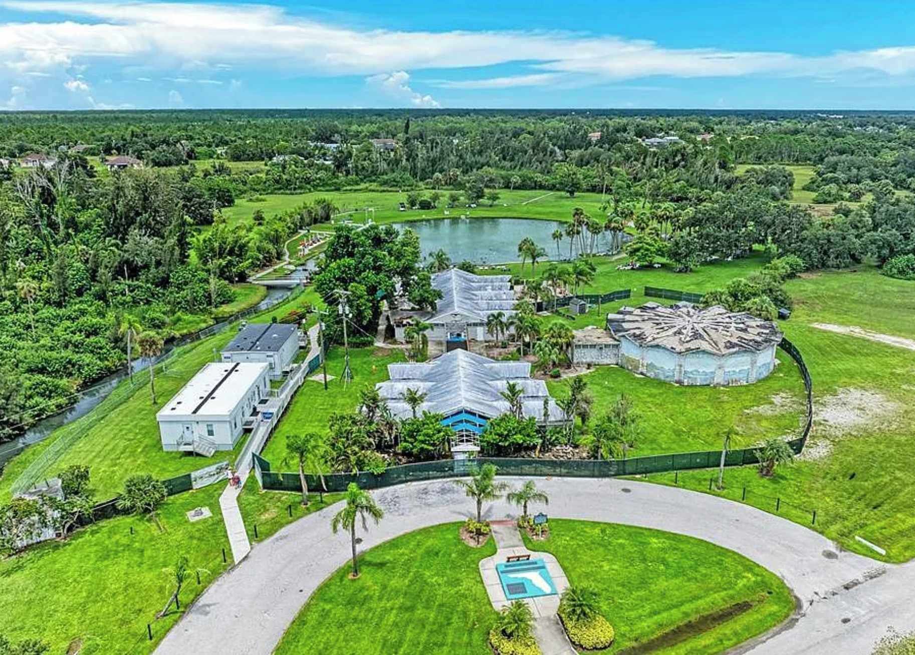 Una vasta proprietà con diversi edifici, una piscina e un lago.