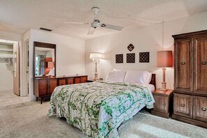 Ein Schlafzimmer mit Bett, Deckenventilator, Kommode, Nachttisch und Lampe.