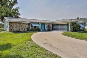 A single-story house with a stone facade, a garage, and a driveway. - Relax, Work, or Play in this Retro Waterfront Home with Sunsets & Private Dock (Port Charlotte)