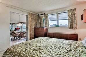 Ein Schlafzimmer mit einem Bett, einem Schminktisch, einem Spiegel und einem Fenster mit Vorhängen.