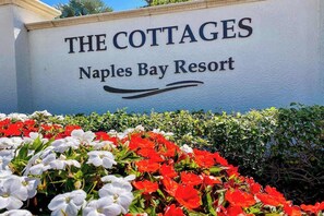 Schild für 'The Cottages' im Naples Bay Resort, mit floralem Dekor.