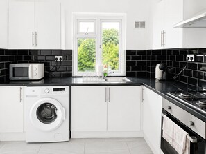 A modern kitchen with a washing machine, microwave, and stove. - Stunning 2-bedroom apartment in charming Newport perfect for relaxing stay (Newport)