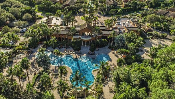 Vista aerea di un resort con piscina centrale, numerosi edifici e vegetazione circostante.