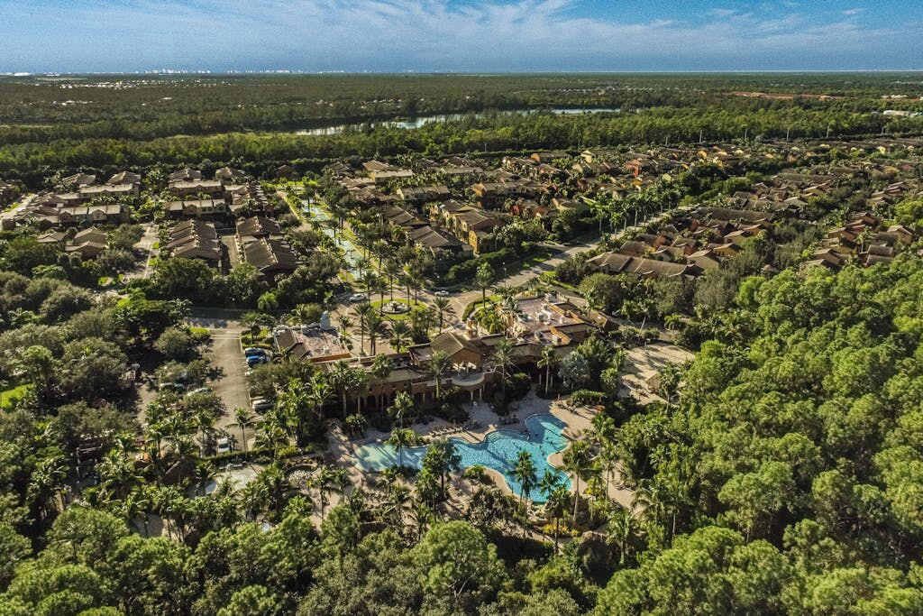 Vue aérienne d’un complexe hôtelier comprenant plusieurs bâtiments, une piscine et une végétation luxuriante.