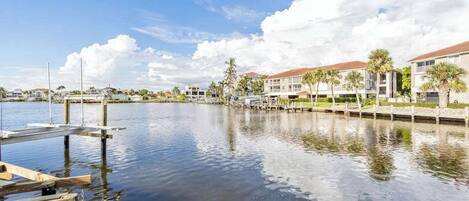 A marina with docked boats, a calm water body, and buildings with a uniform architectural style in the background.