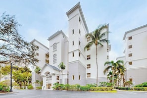 A multi-story hotel with a symmetrical facade, large windows, and a central entrance. - Luxurious condo with on-site pool, private extended balcony, & W/D (Naples)