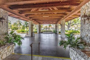 A covered outdoor area with stone pillars, a flat concrete floor, and potted plants. - Water view condo with WiFi, screened balcony, pool, tennis, & on-site dining (Naples)