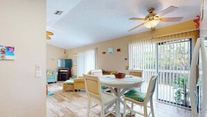 A dining area with a round table and chairs, a ceiling fan, and a view through large windows. - Pool, Game Room & Waterfront | 30+ Days (Port Charlotte)