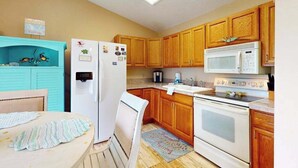 A kitchen with wooden cabinets, a white refrigerator, a microwave, and a stove. - Pool, Game Room & Waterfront | 30+ Days (Port Charlotte)