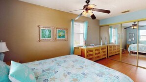 A bedroom with a bed, dresser, mirror, ceiling fan, and framed pictures on the wall. - Pool, Game Room & Waterfront | 30+ Days (Port Charlotte)