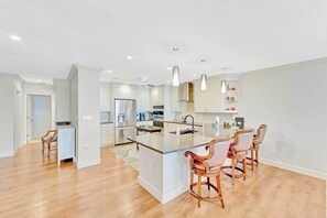 Una cocina moderna con una isla central, taburetes de bar y electrodomésticos integrados.