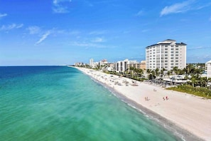 A coastal hotel with a beach view, multiple floors, and a clear sky. - Exquisite home with private pool, washer & dryer, and bikes (Naples)