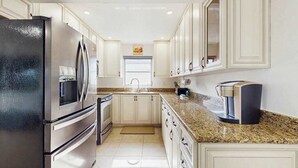 A kitchen with white cabinets, a stainless steel refrigerator, a coffee maker, and a microwave. - Contemporary and cozy home with heated pool, central location, close to beaches (Naples)