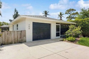 Einbungalow mit Garage, überdachter Veranda und umzäunter Garten.