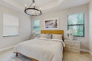 Ein Schlafzimmer mit einem Bett, Nachttischen, einem Chandelier und einem gerahmten Bild an der Wand.