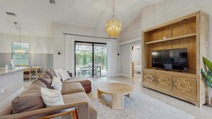 Un salon moderne avec un canapé, une table basse, un téléviseur et un meuble en bois.